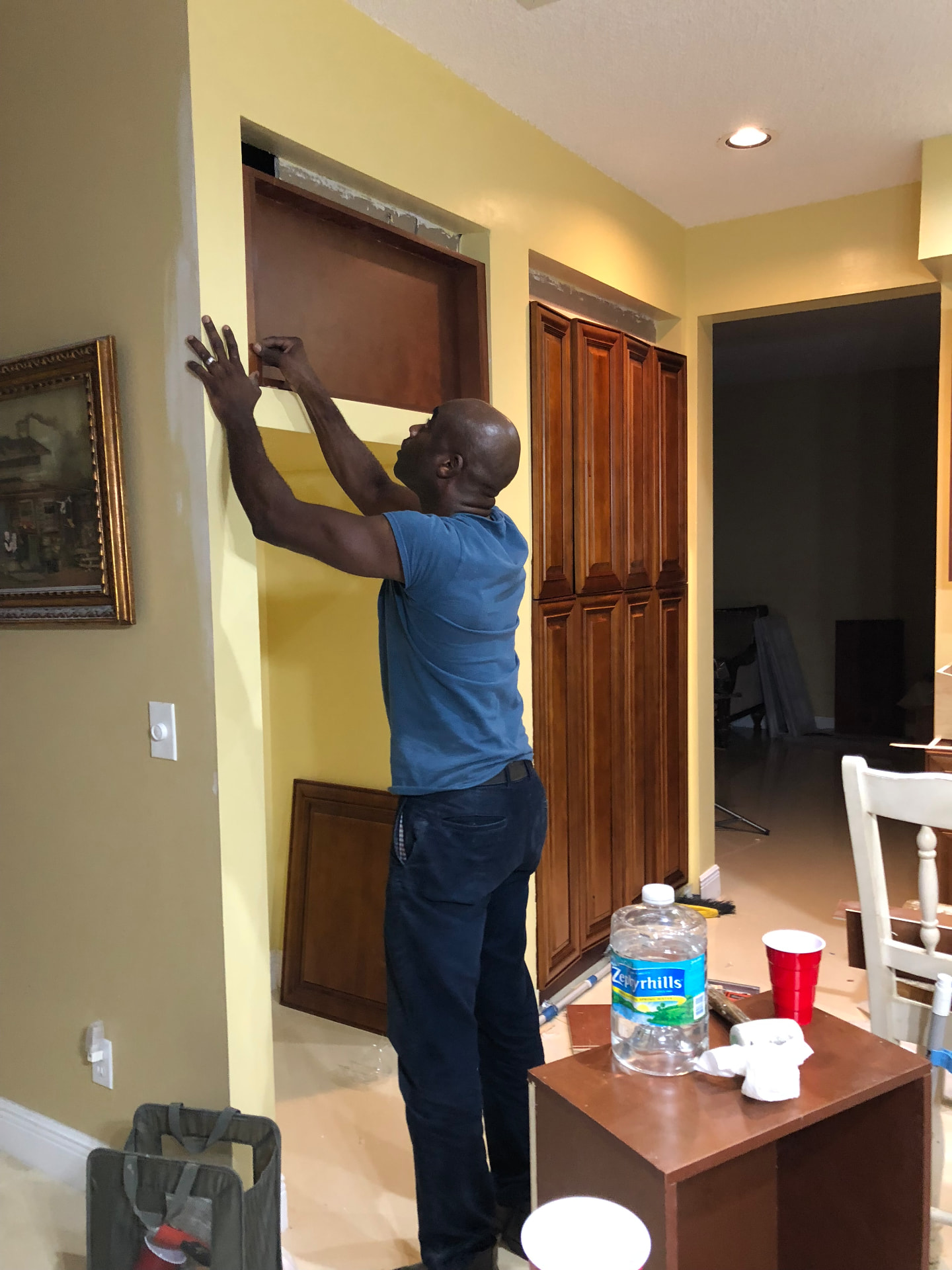 Craftsman installing upper cabinet box during the Cooper City kitchen build