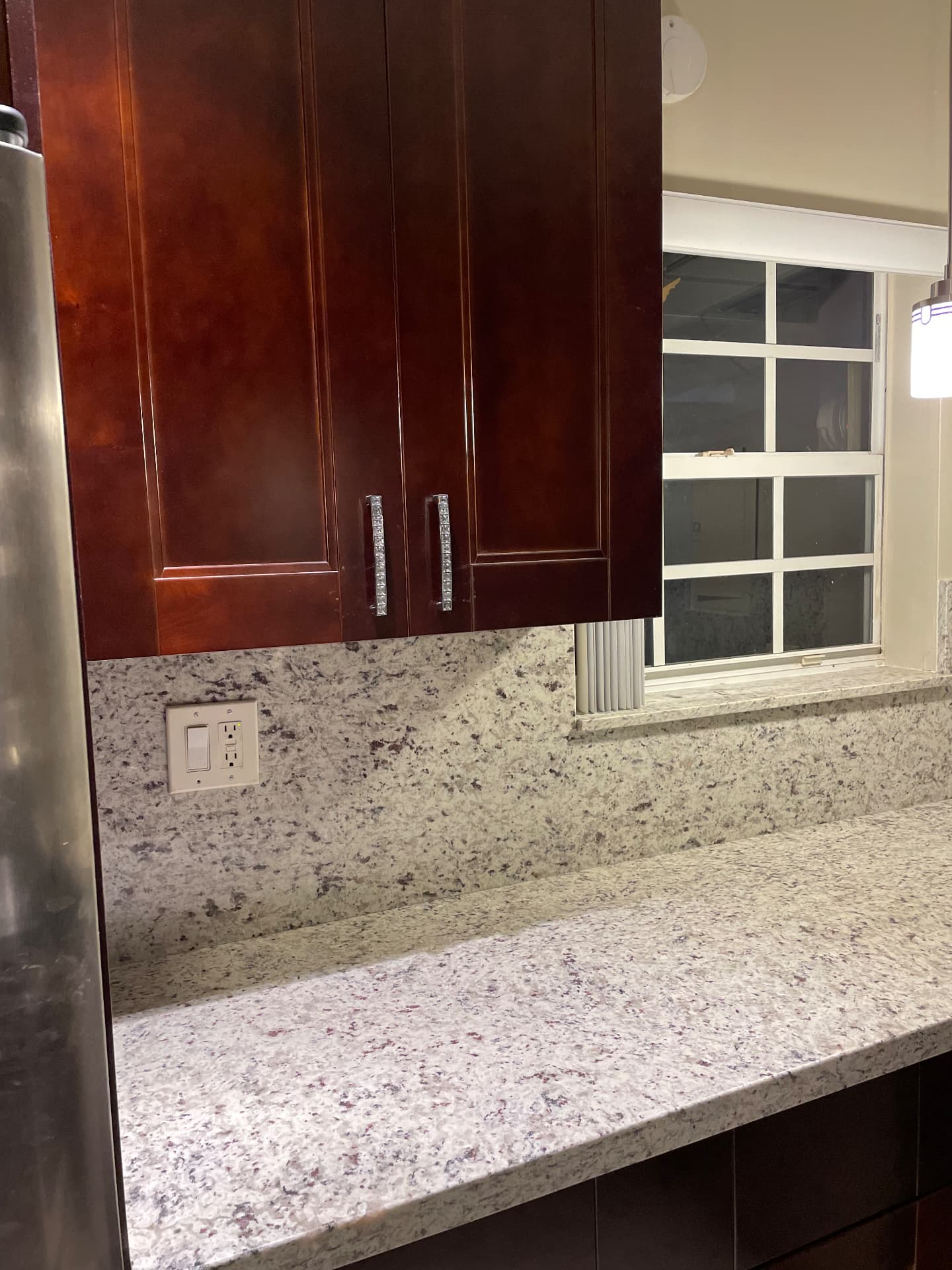 Completed counter run beside the window with granite backsplash and mahogany uppers