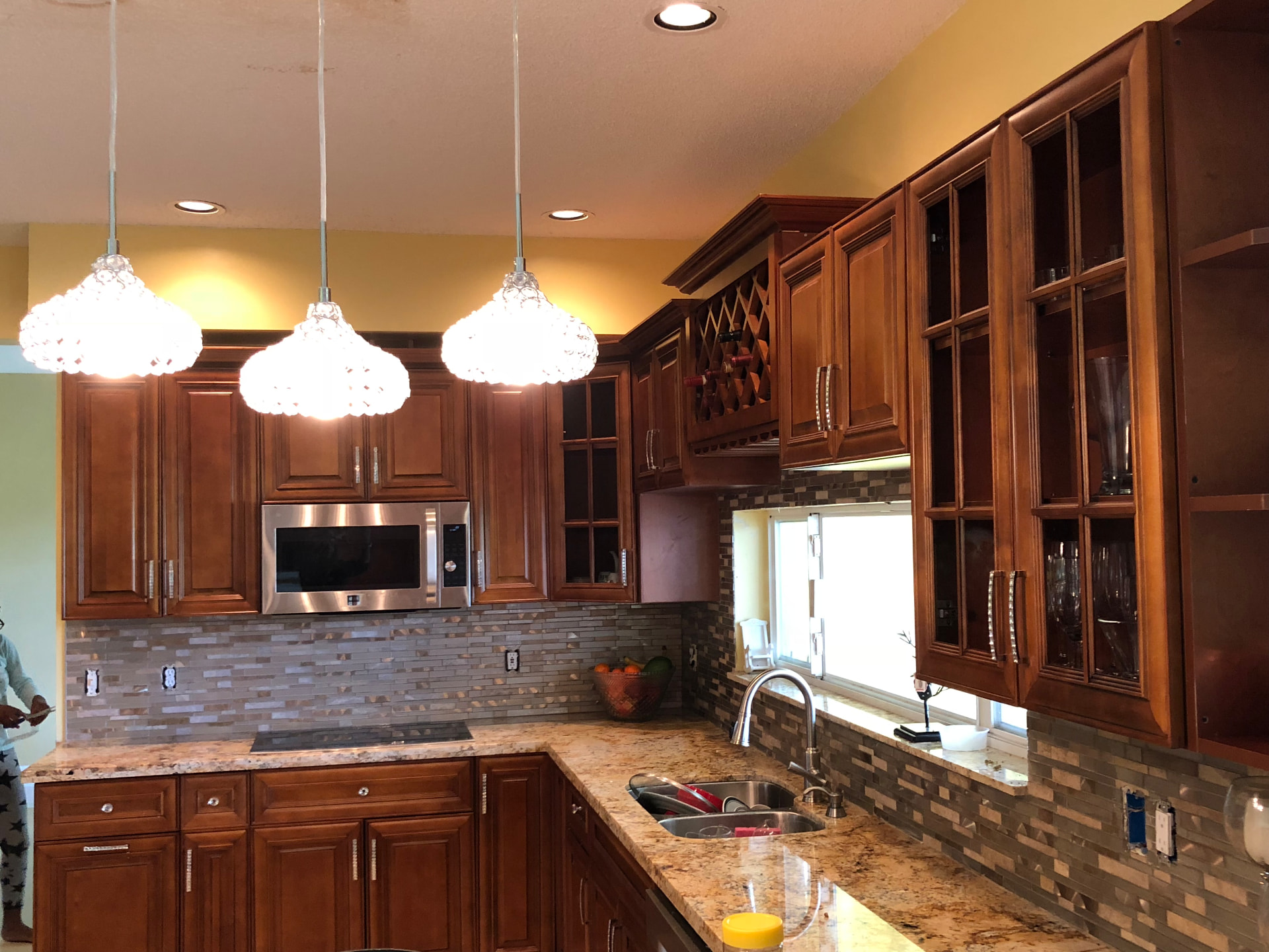 Completed kitchen with glass mosaic backsplash, wine rack and glass-front upper cabinets