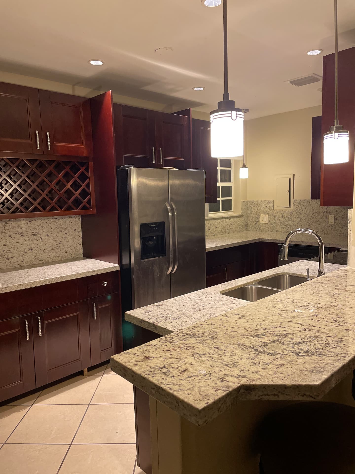 Completed North Miami Beach kitchen with mahogany cabinetry, granite peninsula and pendant lighting