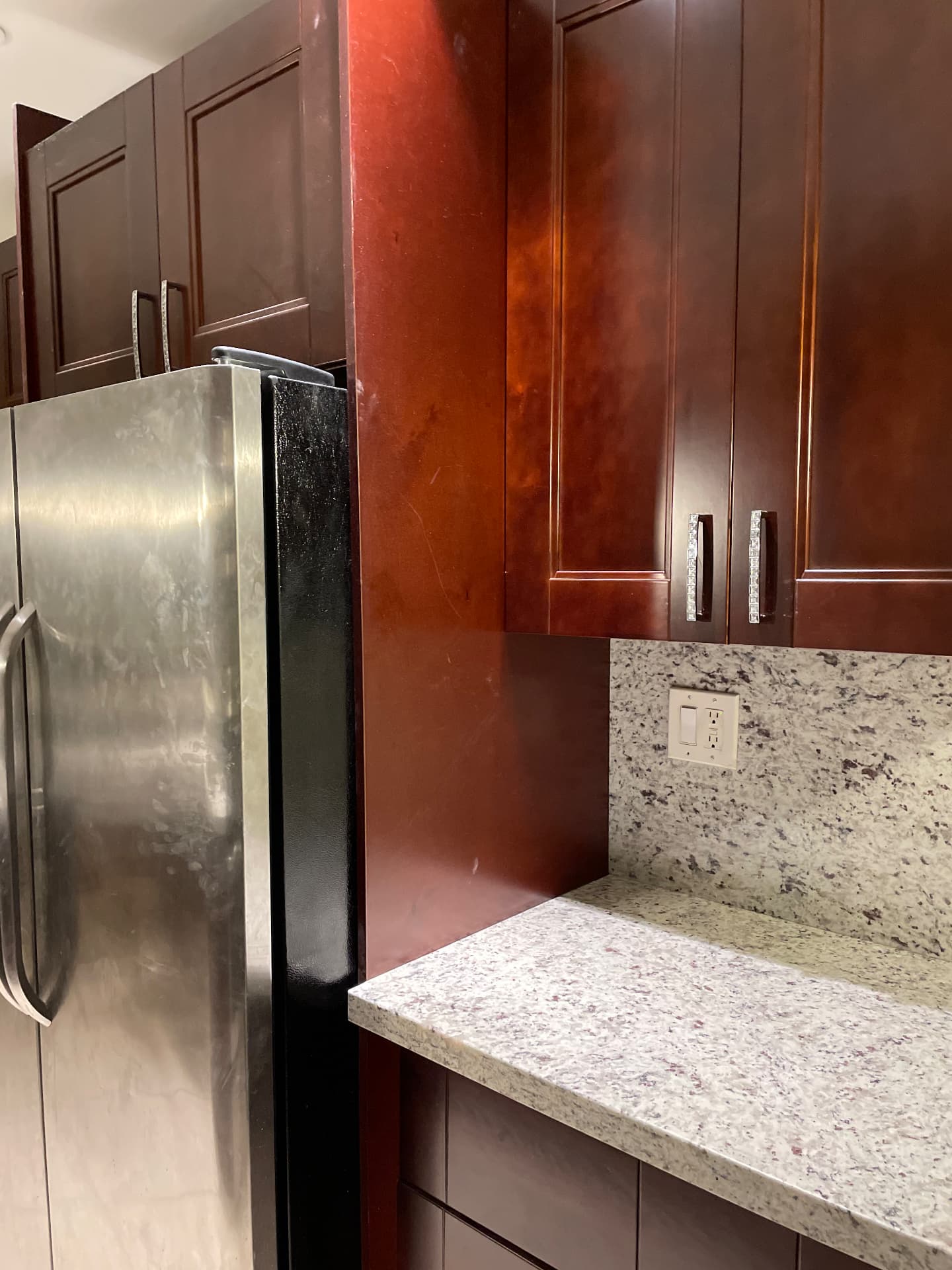 Completed refrigerator surround with tall mahogany cabinetry and granite counter