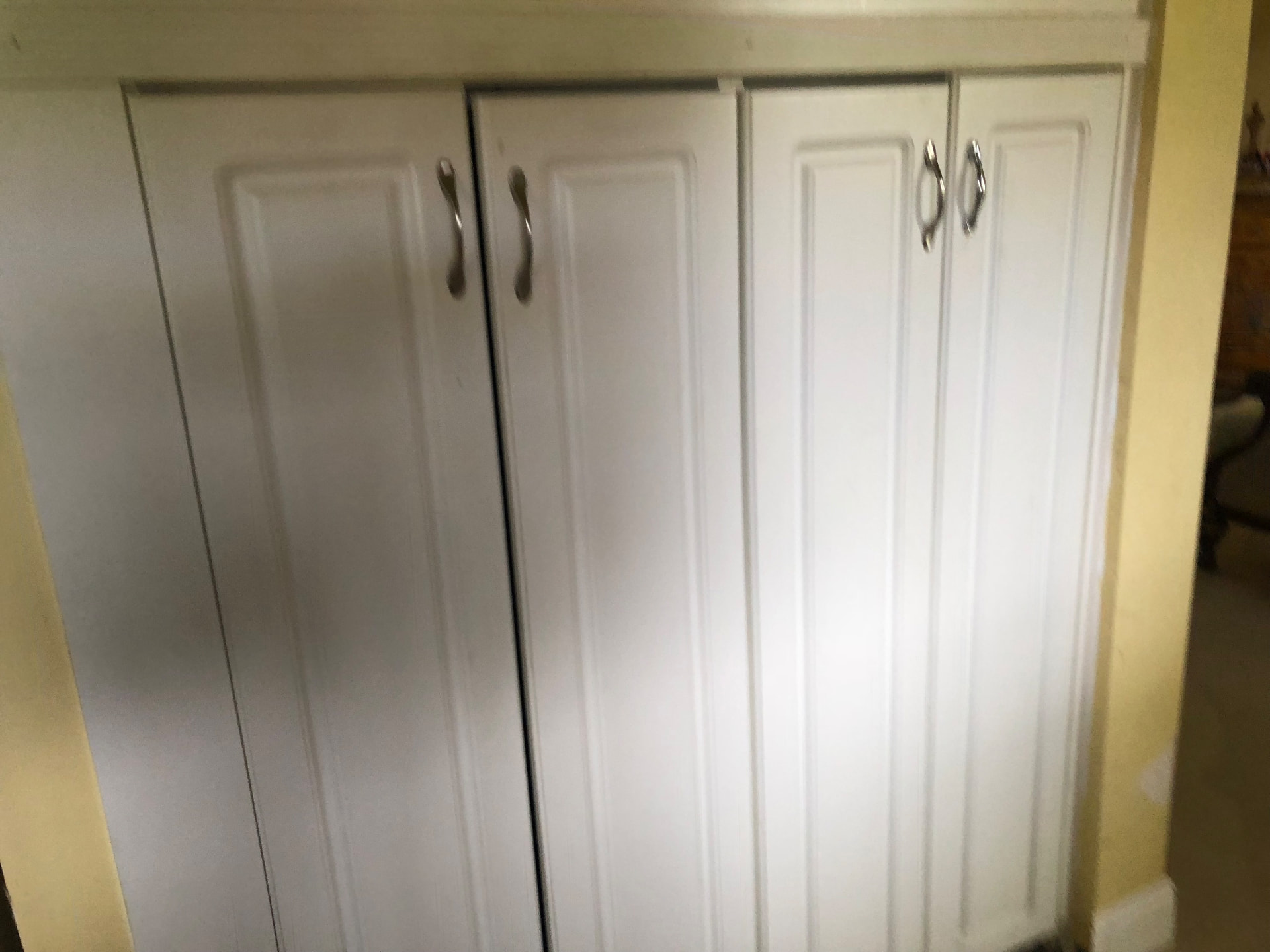 Existing dated white pantry cabinet doors before kitchen remodeling