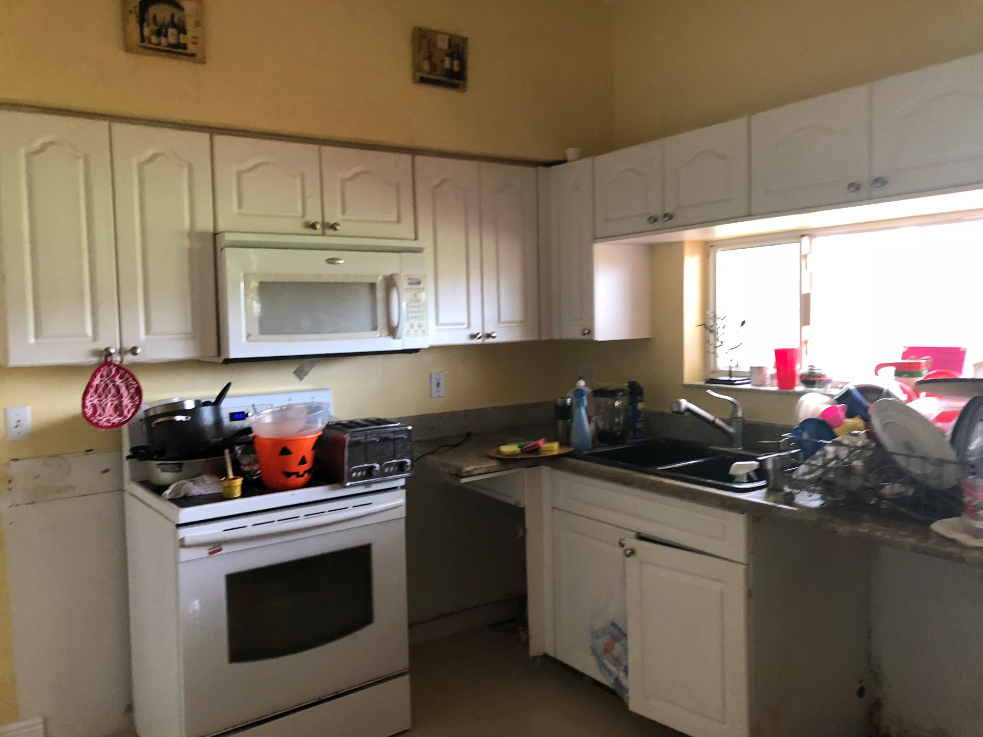 Existing L-shaped kitchen layout before remodeling with laminate counters and arched cabinet doors