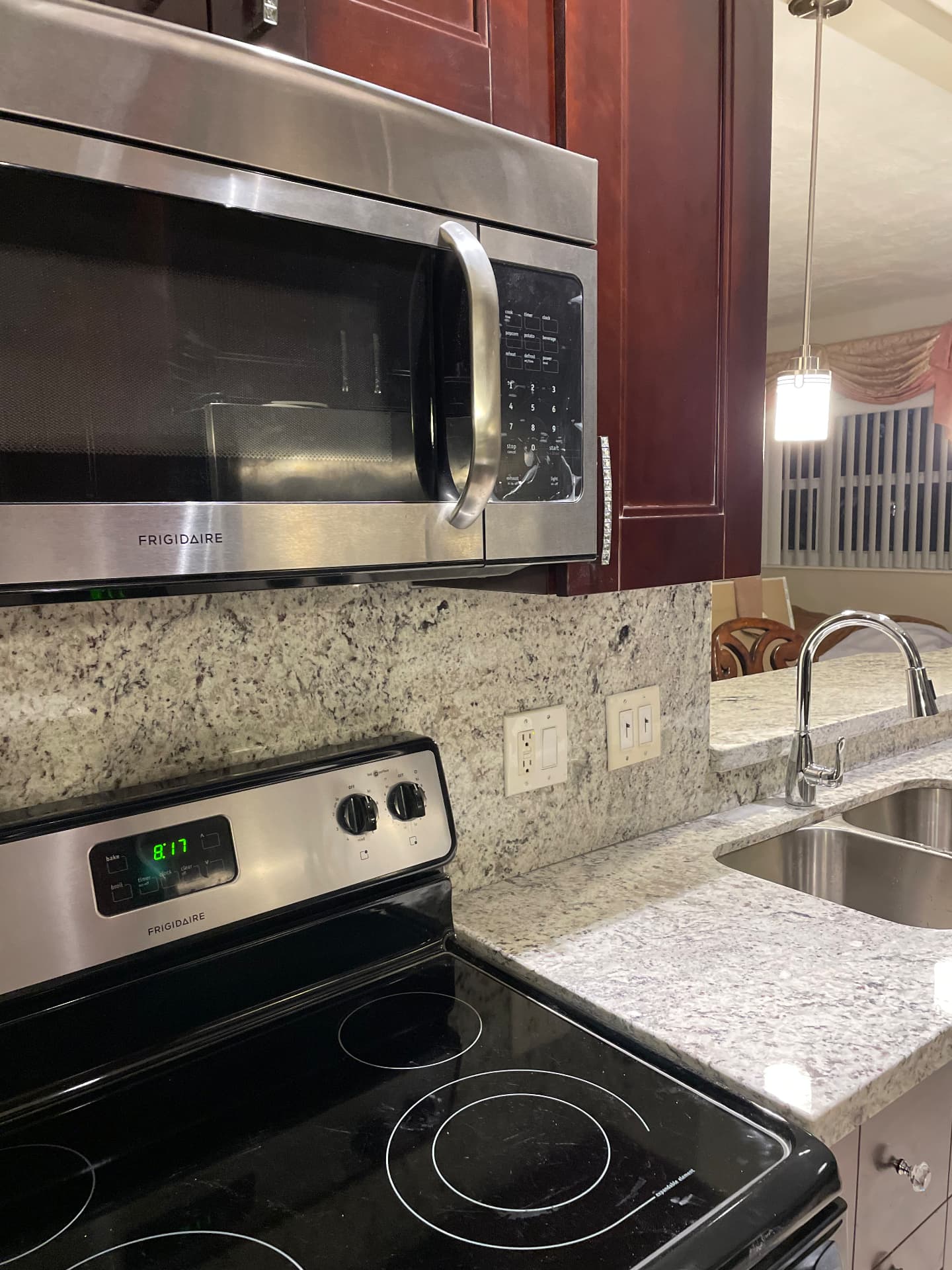 Completed range wall with over-range microwave, granite backsplash and chrome faucet